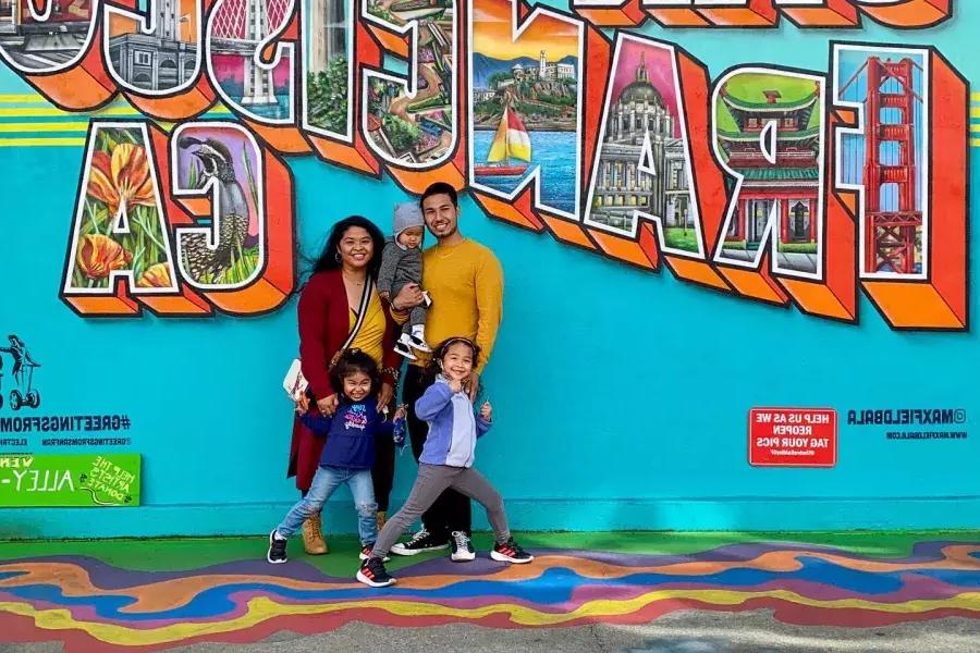 Une famille posant pour une photo devant une fresque murale de San Francisco