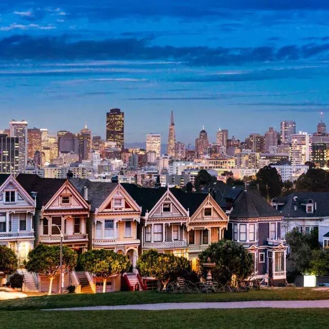 Les célèbres 浓的女人 d'Alamo Square sont représentées devant l'horizon de 贝博体彩app au crépuscule.